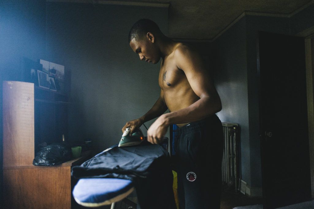 Logan Sloan, 20, irons his graduation gown at home as he prepares for his graduation ceremony later in the day, at which he will receive his high school diploma from the Covenant House Academy in Detroit, Michigan. June 14th, 2016.